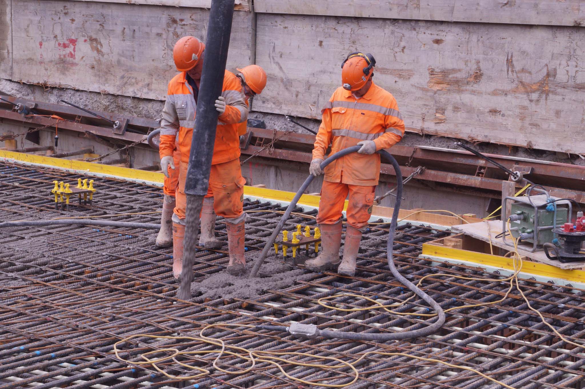 Drei Bauarbeiter füllen den Boden mit Zement