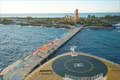 Blick auf einen Pier mit bunten Sonnensegeln am Meer.