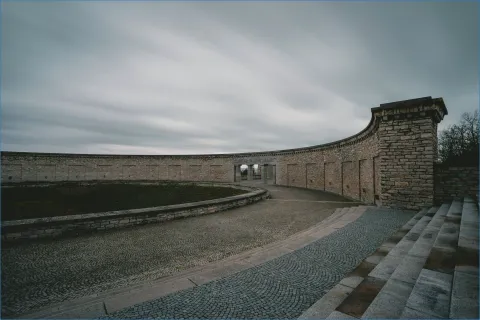 Steinmauer mit Rundbogen und Wolkenhimmel