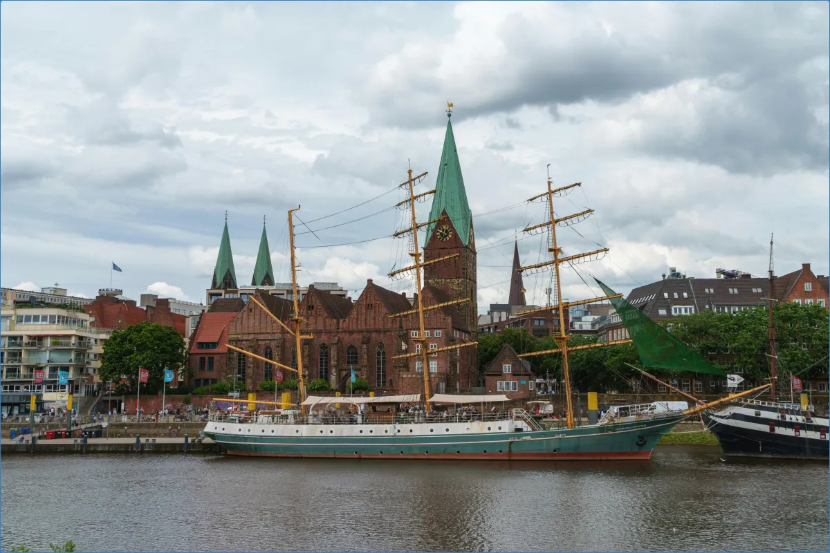 Segelschiff vor historischer Kirche am Fluss