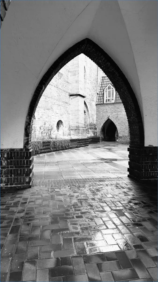 Gotischer Torbogen mit gepflastertem Boden.