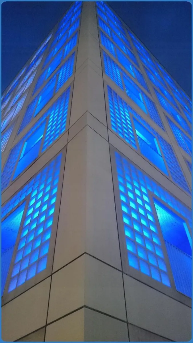 Eckansicht eines Gebäudes mit blauer Beleuchtung.