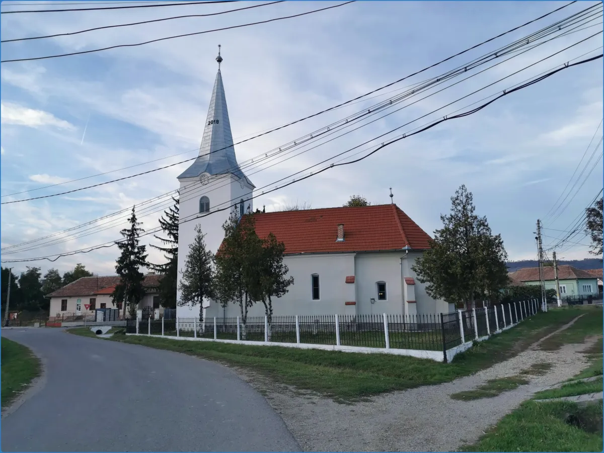 Kirche mit Turm und rotem Dach in ländlicher Umgebung