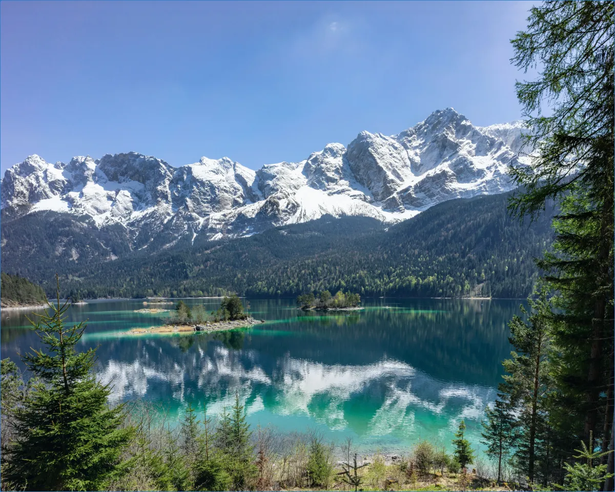 Bergsee mit schneebedeckten Bergen im Hintergrund.