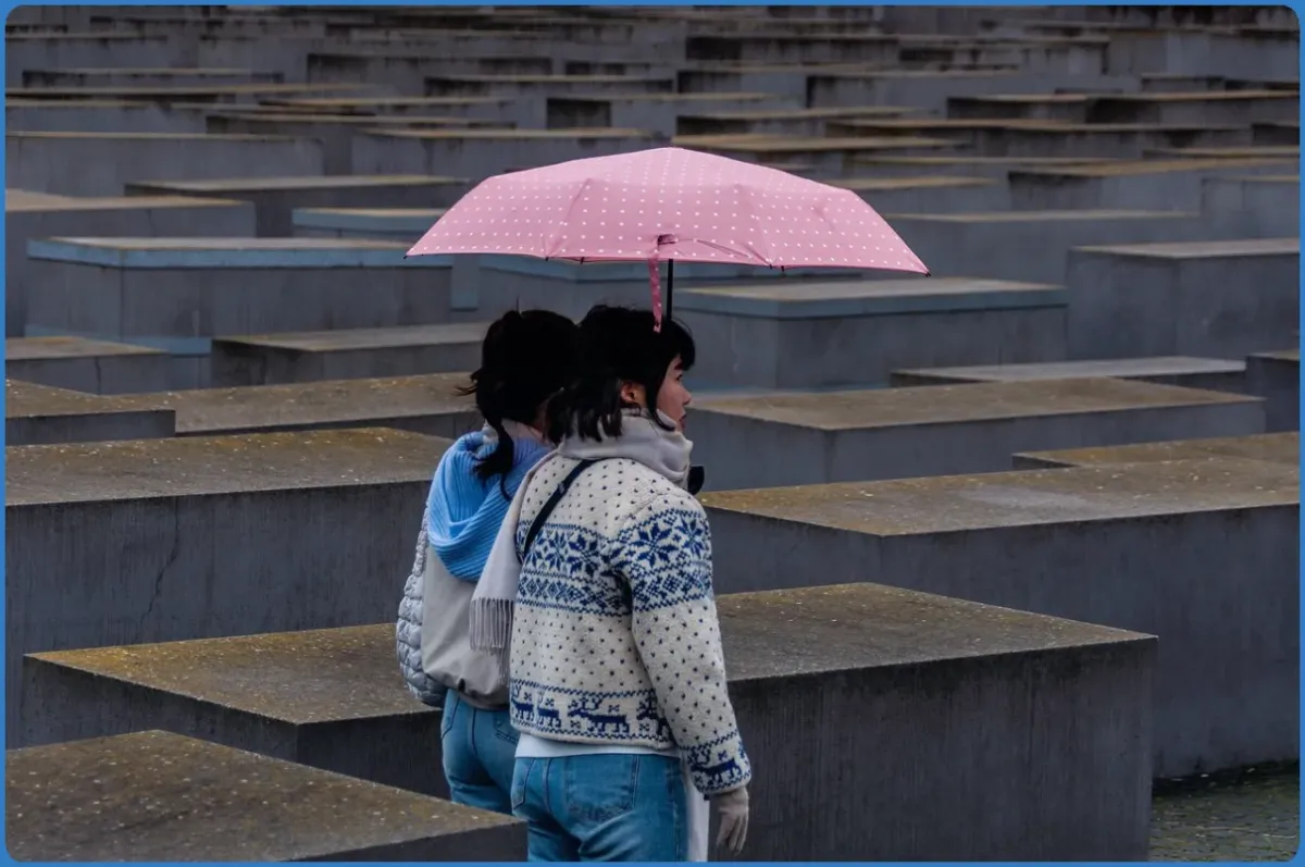 Zwei Personen mit rosa Regenschirm im Denkmal.