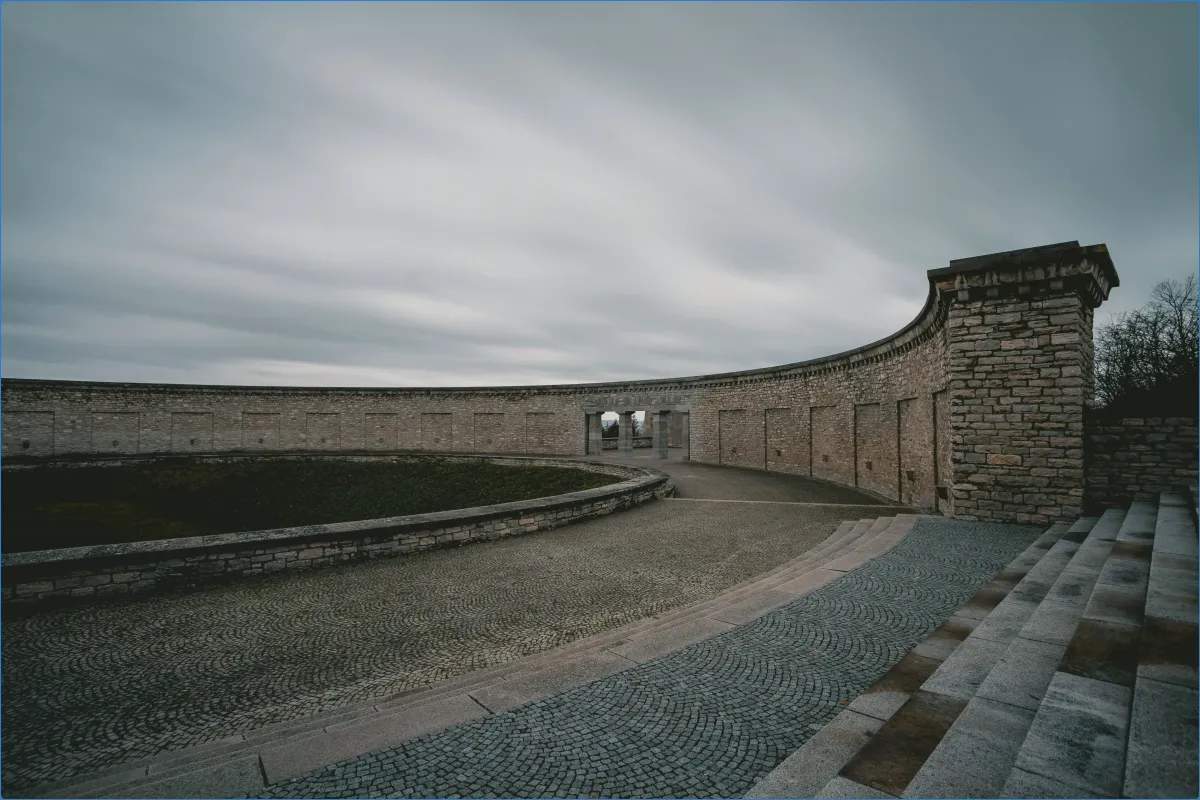 Steinmauer mit Rundbogen und Wolkenhimmel