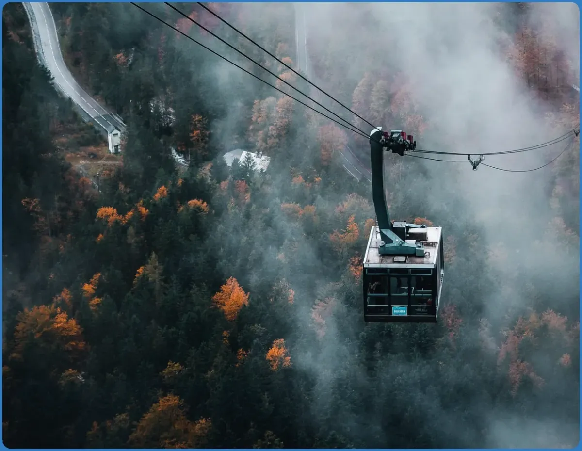 Seilbahn über nebligem Wald im Herbst
