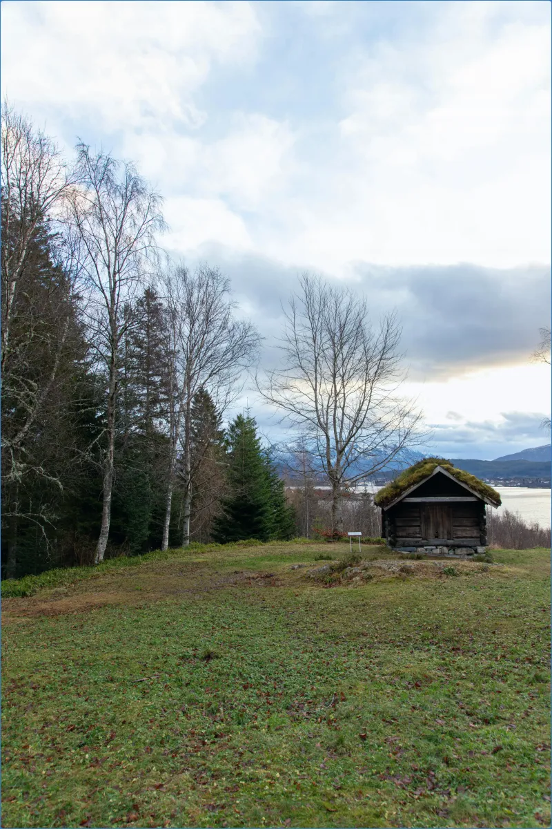 Kleine Holzhütte in einer Waldlandschaft.