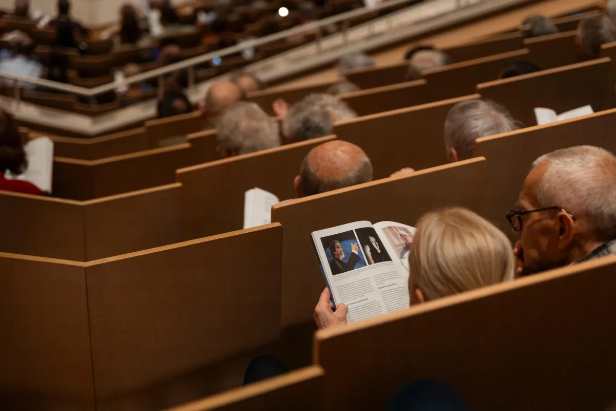 Personen in einem Auditorium lesen Programme.