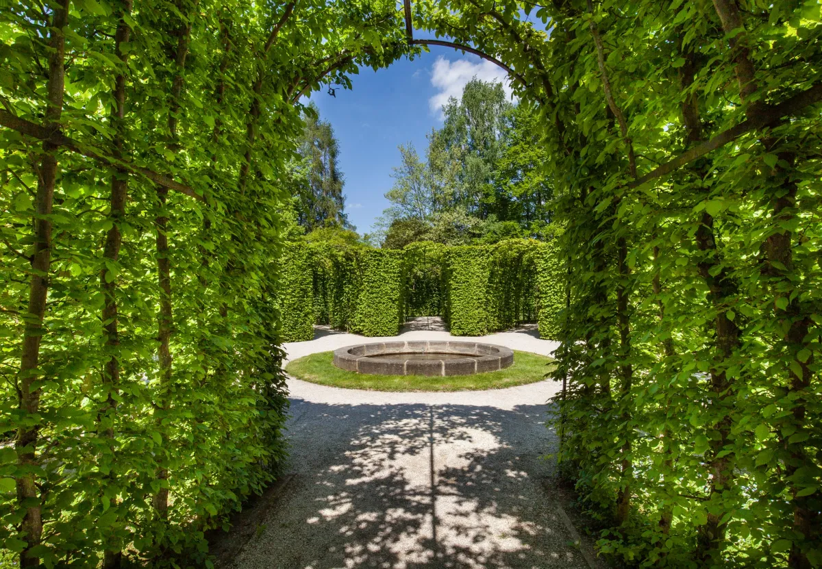 Grüner Laubengang mit Rundbeet im Garten