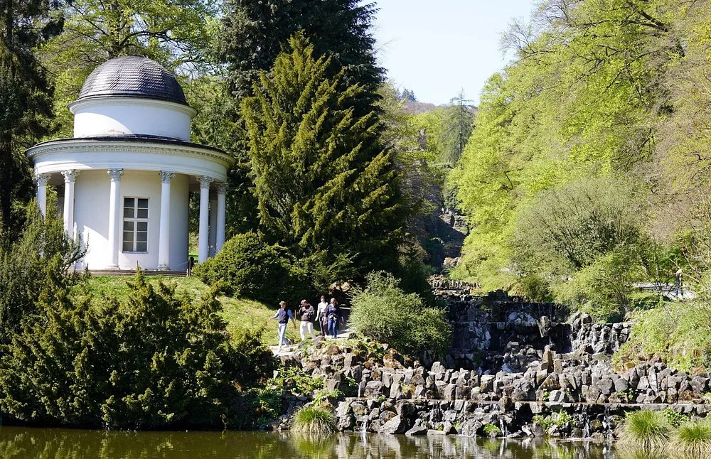 Weißer Pavillon im Park mit Bäumen und Menschen