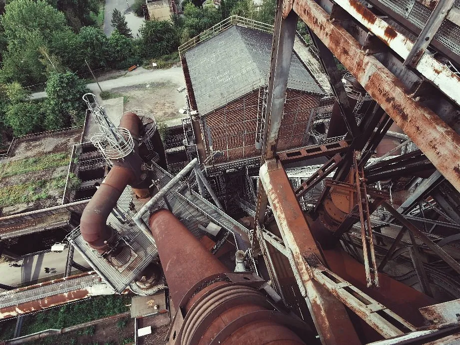 Industrieruine mit rostigen Rohren und Gebäuden.