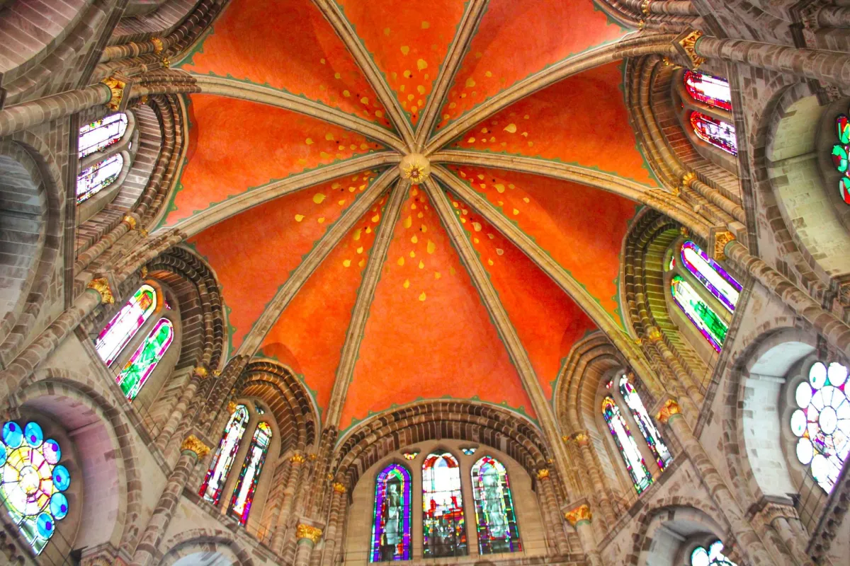 Blick auf eine verzierte Kirchenkuppel mit Buntglasfenstern.