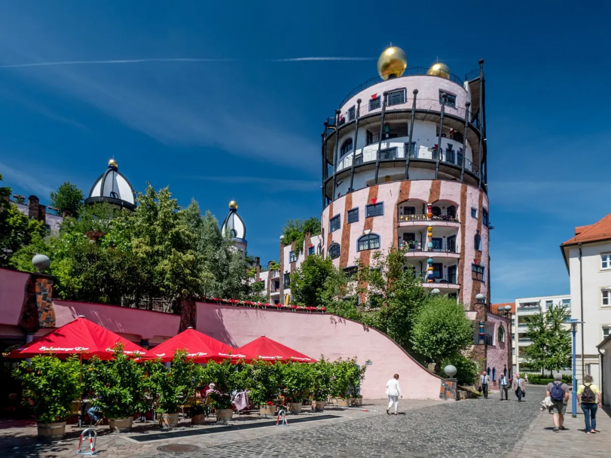 Buntes Gebäude mit goldenen Kuppeln und rotem Sonnenschirm.