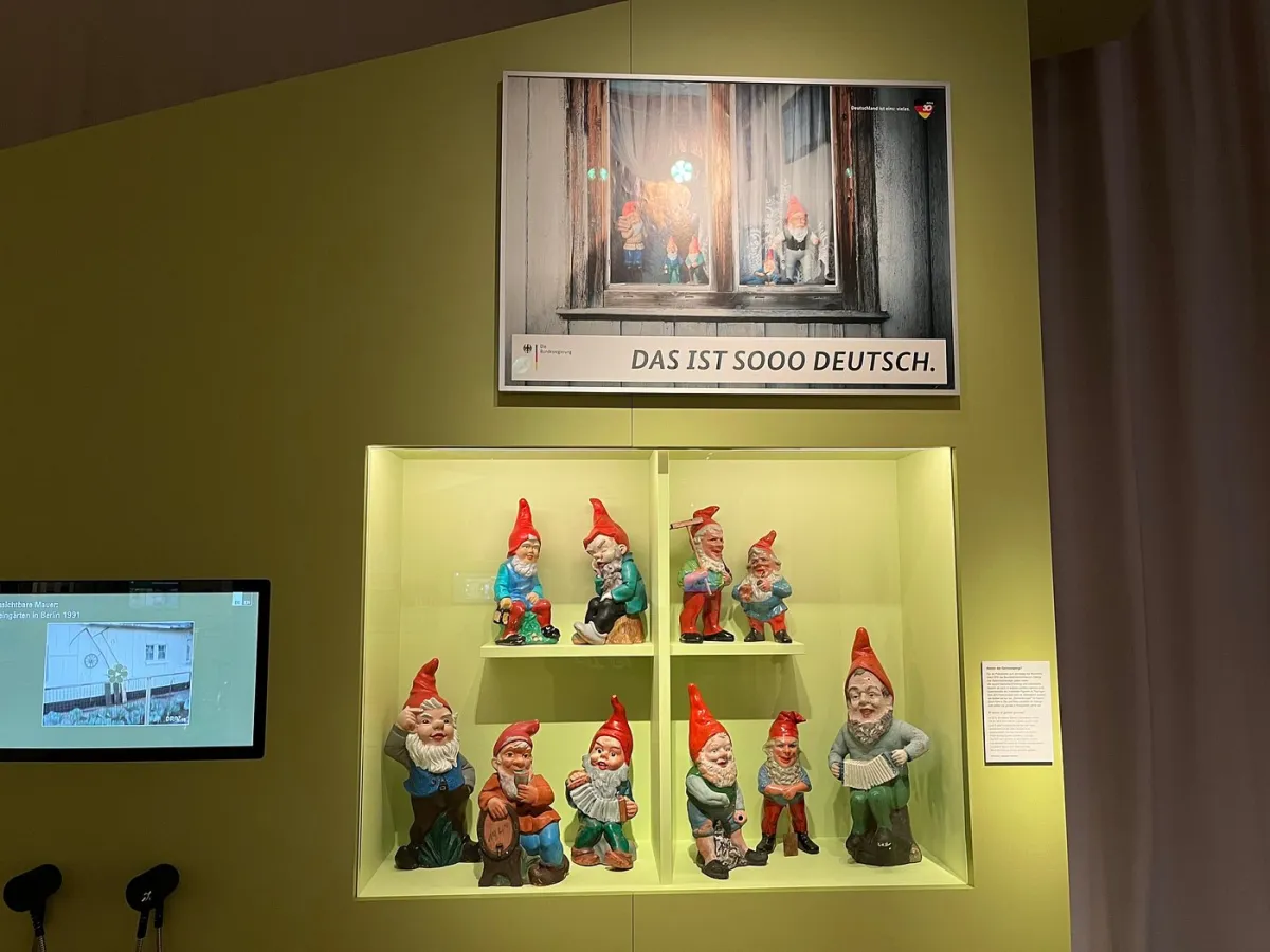 Ausstellung mit Gartenzwergen und Poster.