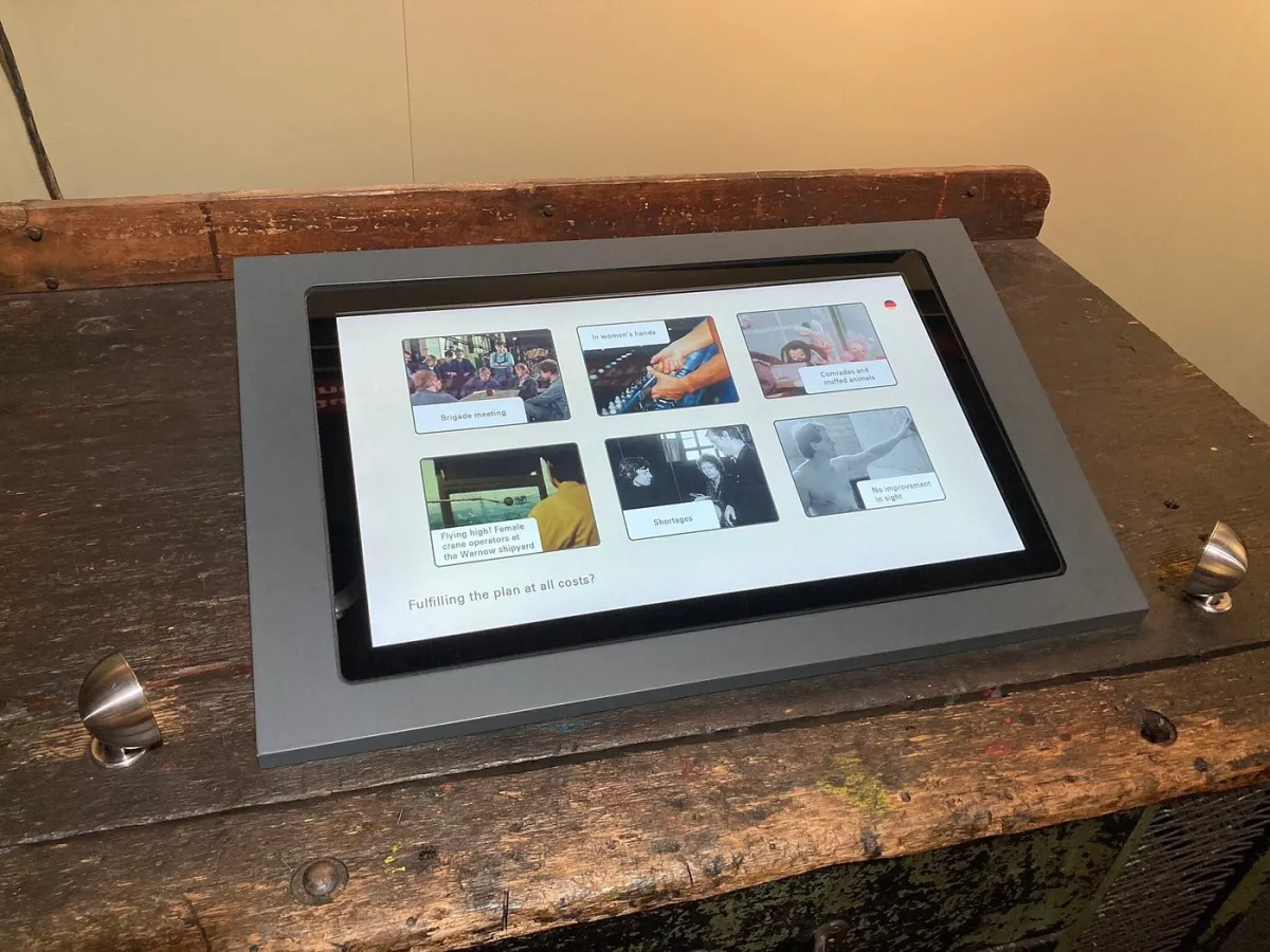 Tablet auf einem Holztisch mit historischen Bildern.