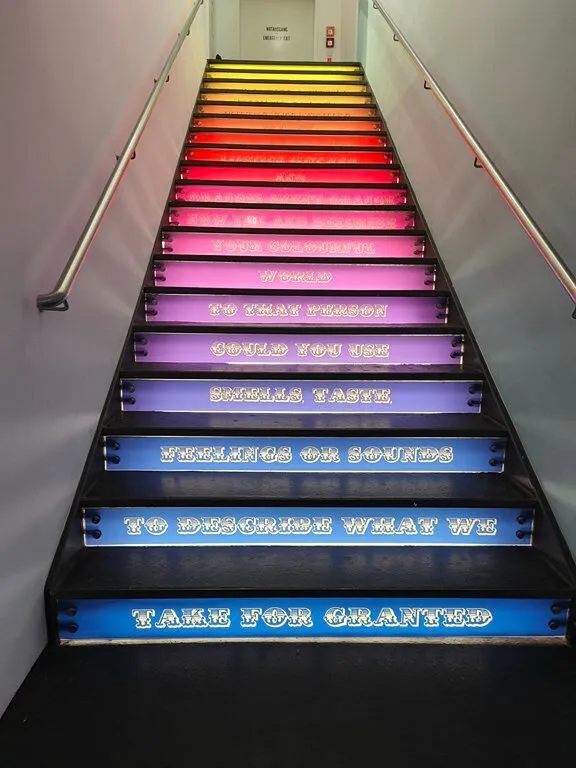 Bunte Treppe mit leuchtendem Text.