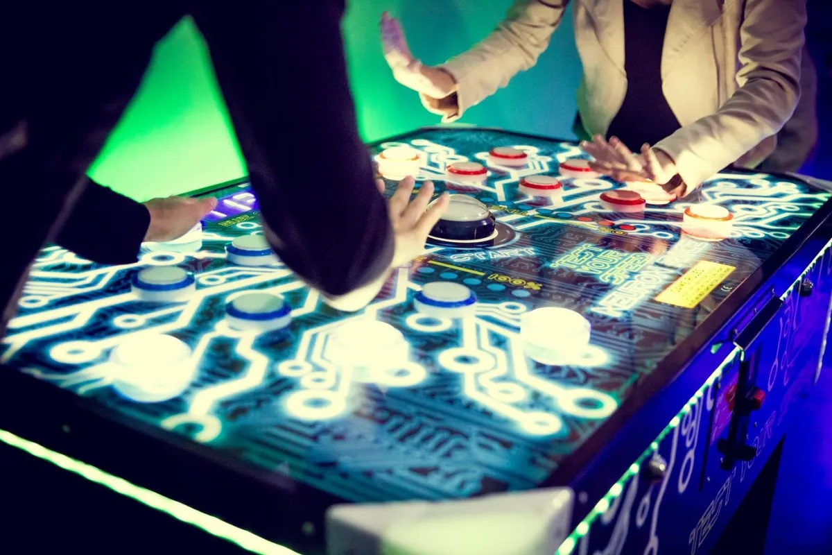 Menschen spielen an einem beleuchteten Arcade-Tisch