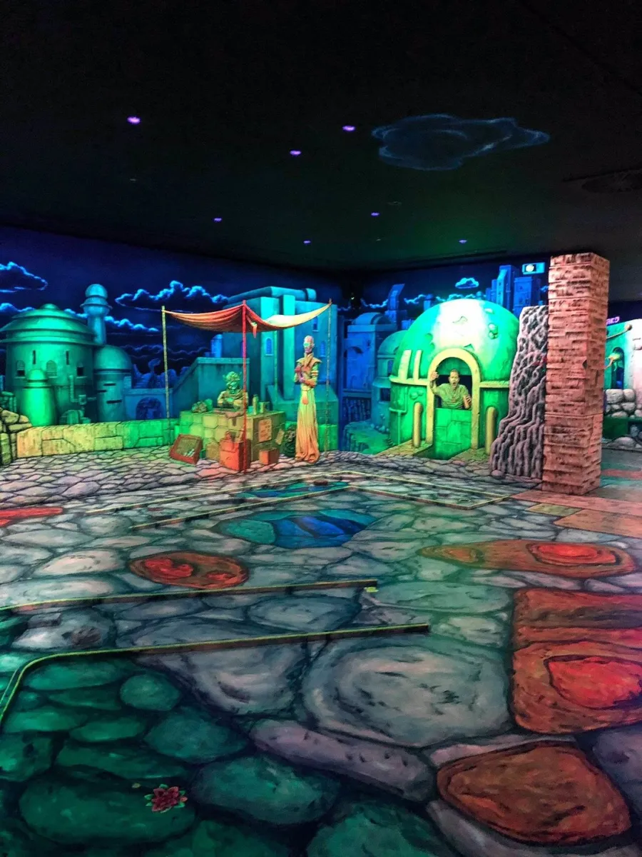 Leuchtende Minigolfbahn mit Fantasy-Dekoration.
