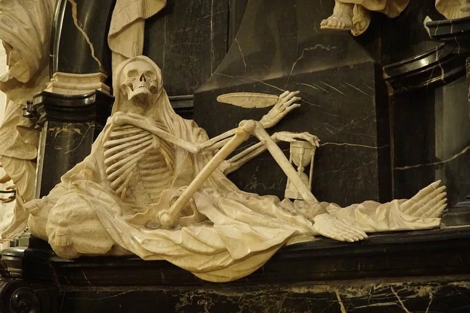 Skulptur eines Skeletts in einem Gewand.