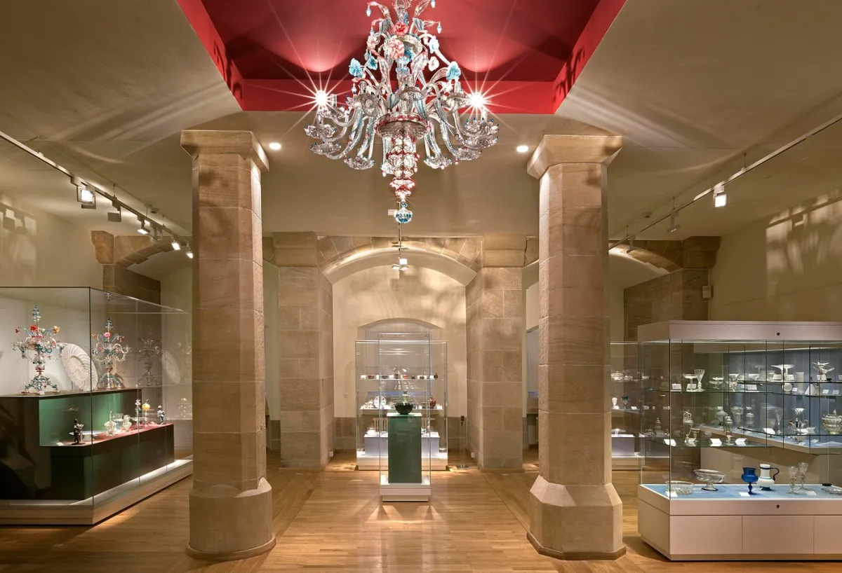 Museumsausstellung mit Glasvitrinen und Kronleuchter.
