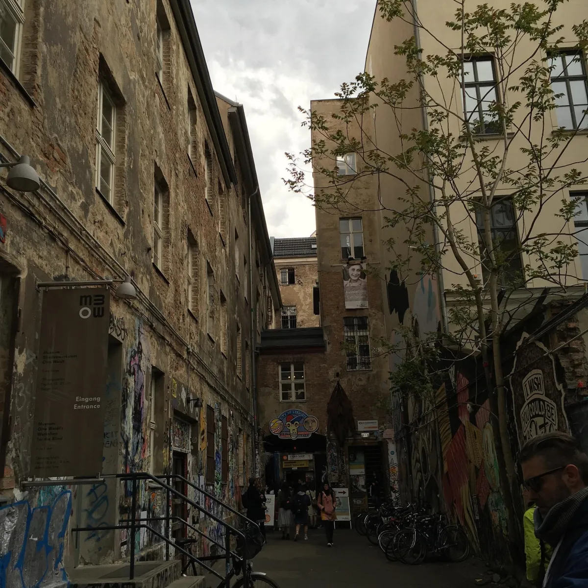 Schmaler Innenhof mit Graffiti und alten Gebäuden.