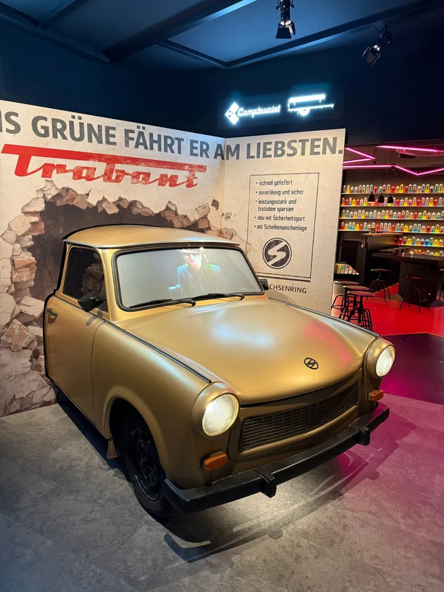 Goldener Trabant vor Werbewand.
