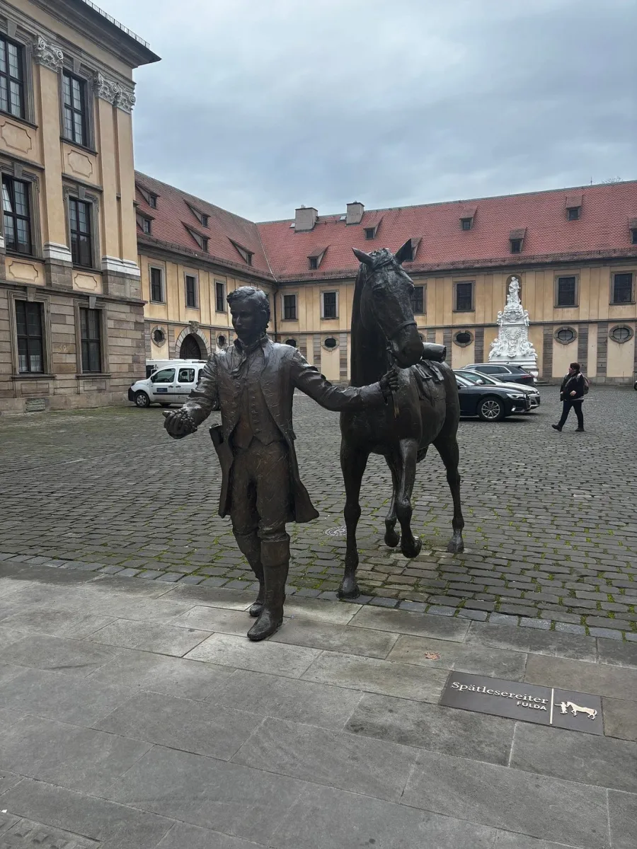 Bronzestatue eines Mannes mit Pferd auf einem Platz.