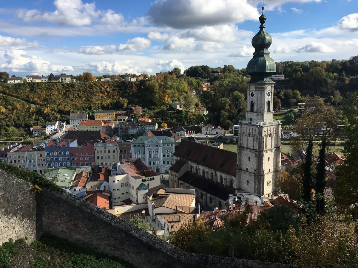 Stadtansicht mit Kirche und Hügeln.