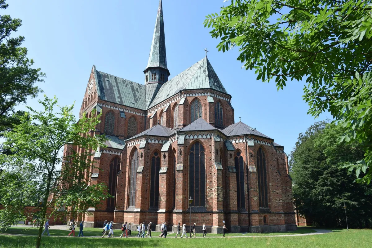 Backsteinkirche mit Turm und Menschen im Vordergrund