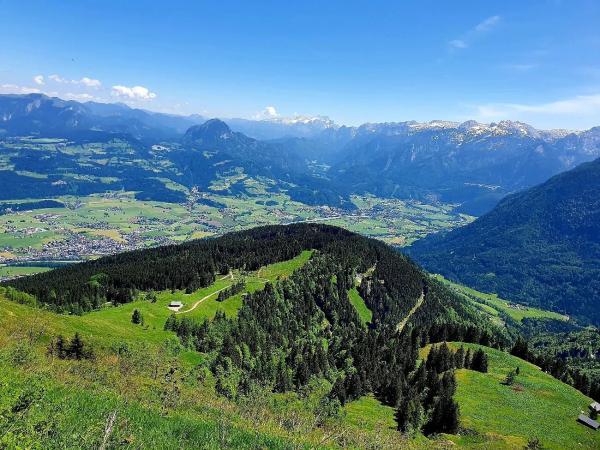Berglandschaft mit grünen Wiesen und Wäldern.