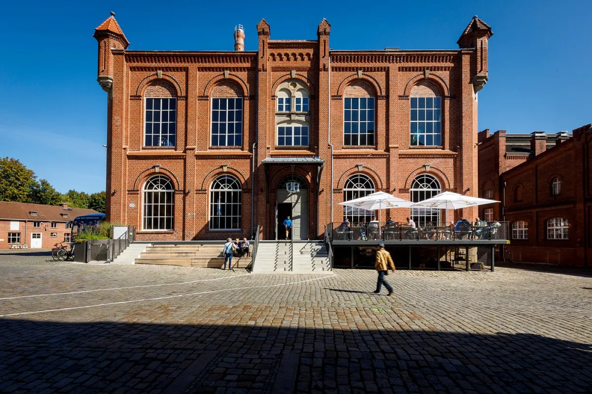 Backstein-Gebäude mit Terrasse und Sonnenschirmen