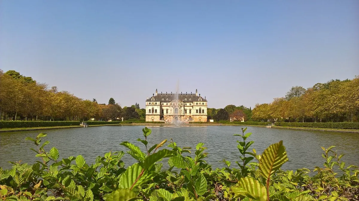 Schloss mit Brunnen und Teich im Vordergrund
