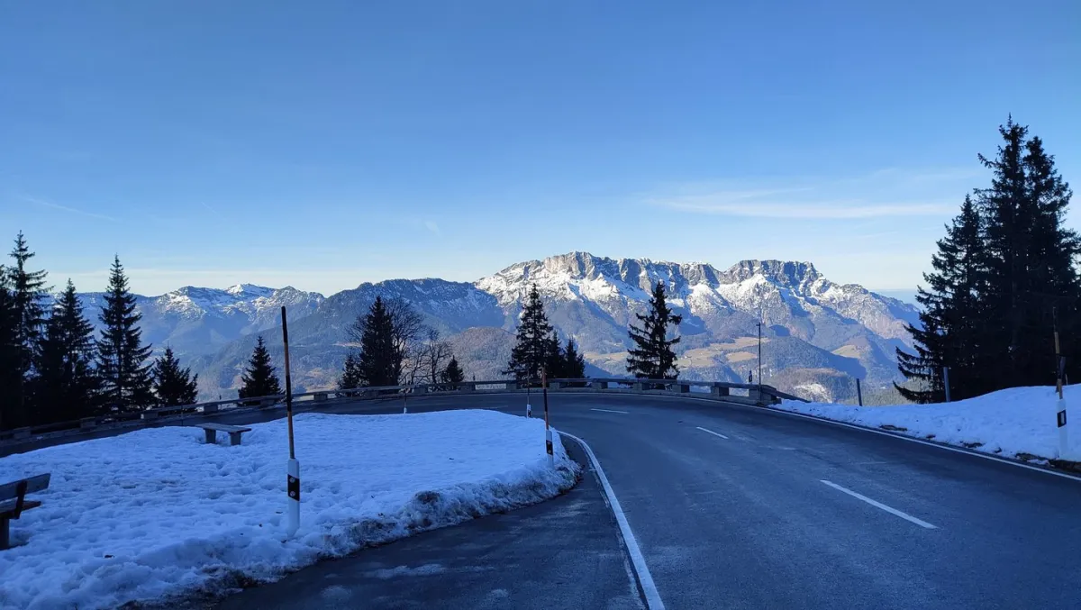 Verschneite Bergstraße mit Alpen im Hintergrund
