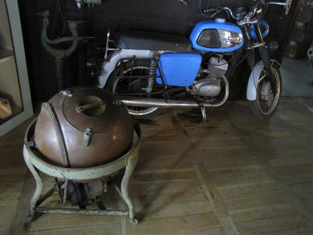 Altes Motorrad und antikes Gerät auf Holzboden.