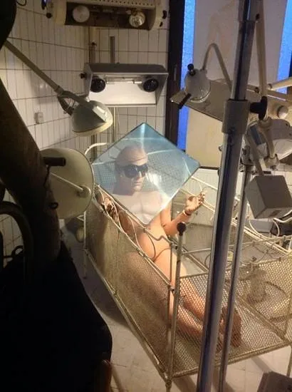 Person in einem Metallbett mit Sonnenbrille und Lampen
