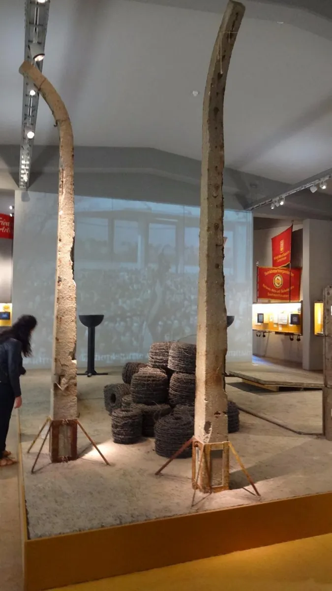 Museumsausstellung mit Betonpfosten und Stacheldrahtrollen.