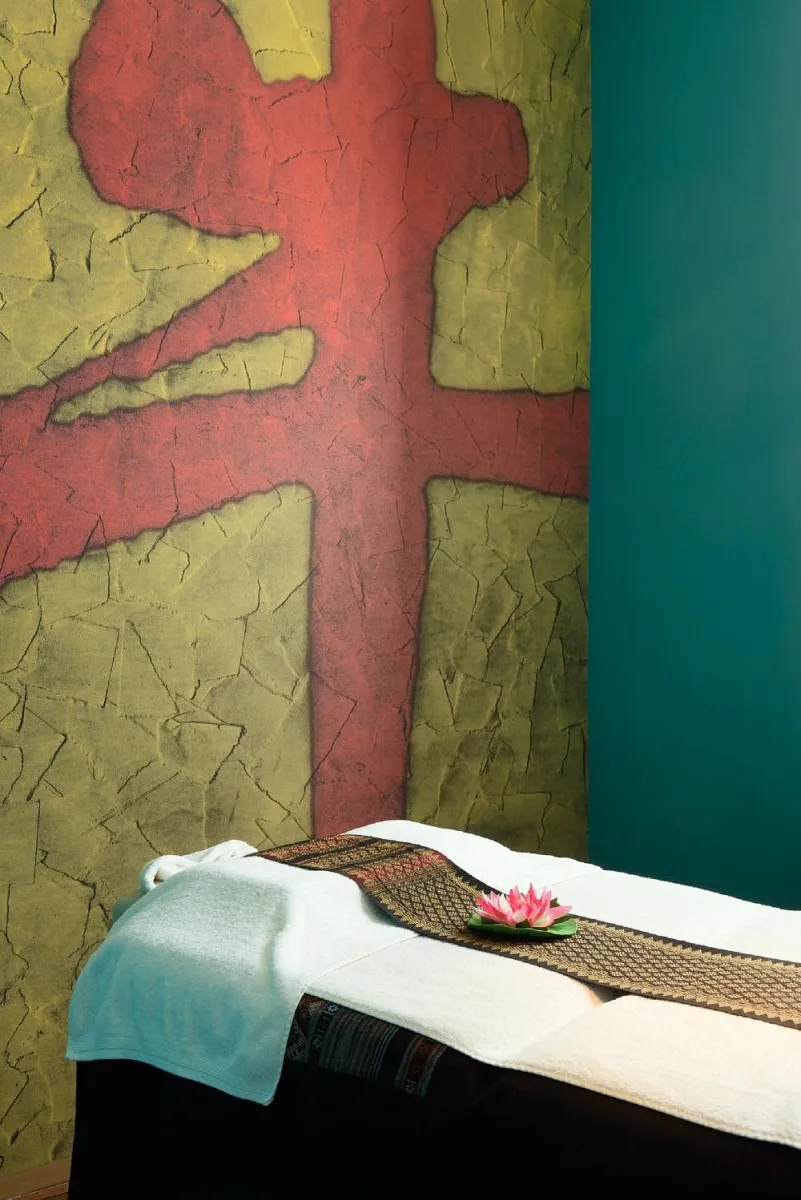 Massageliege mit Lotusblüte in einem Raum mit Wandkunst.