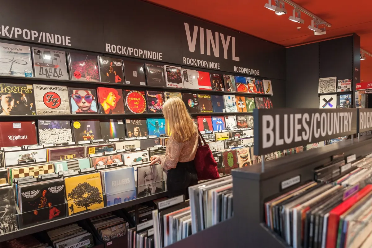 Frau blättert durch Vinyl-Schallplatten in einem Musikgeschäft.
