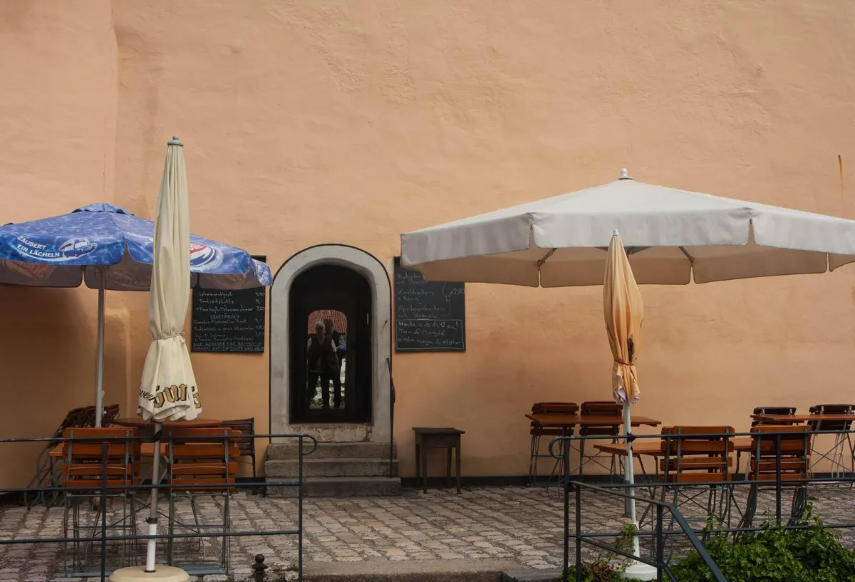 Leerer Außenbereich eines Cafés mit Sonnenschirmen.