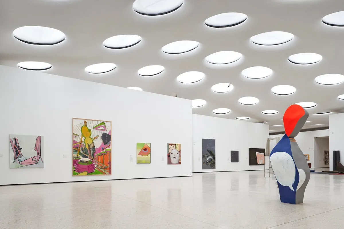Innenansicht einer modernen Kunstgalerie mit Gemälden und Skulptur.