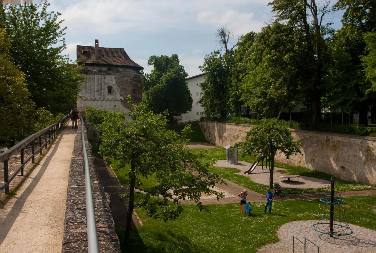 Historische Mauer mit Spielplatz und Bäumen