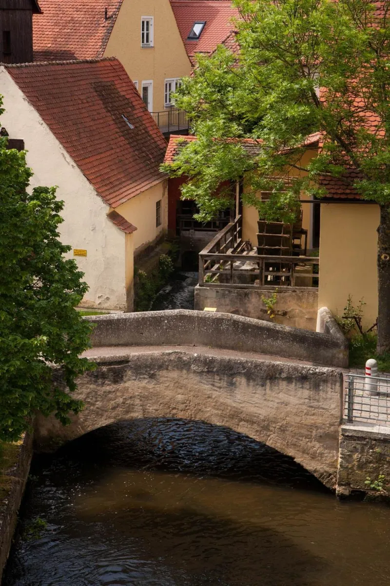 Steinbrücke über einen Fluss mit Häusern im Hintergrund