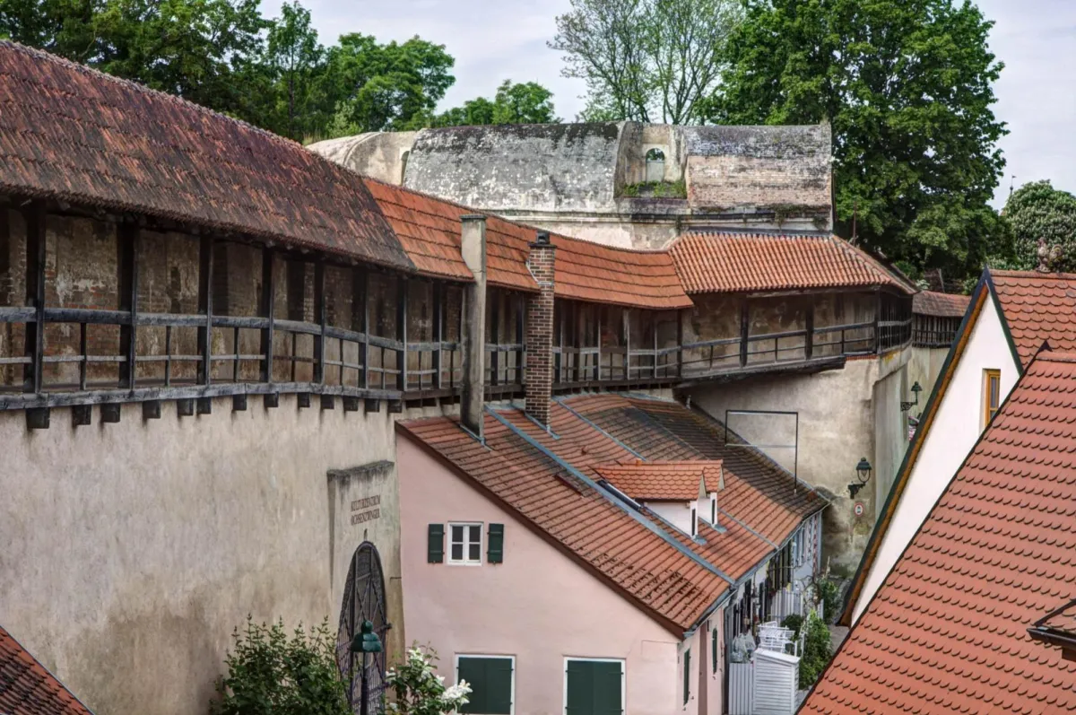 Historische Stadtmauer mit roten Ziegeldächern.