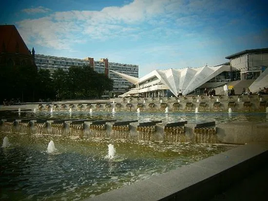 Brunnen mit moderner Architektur im Hintergrund.