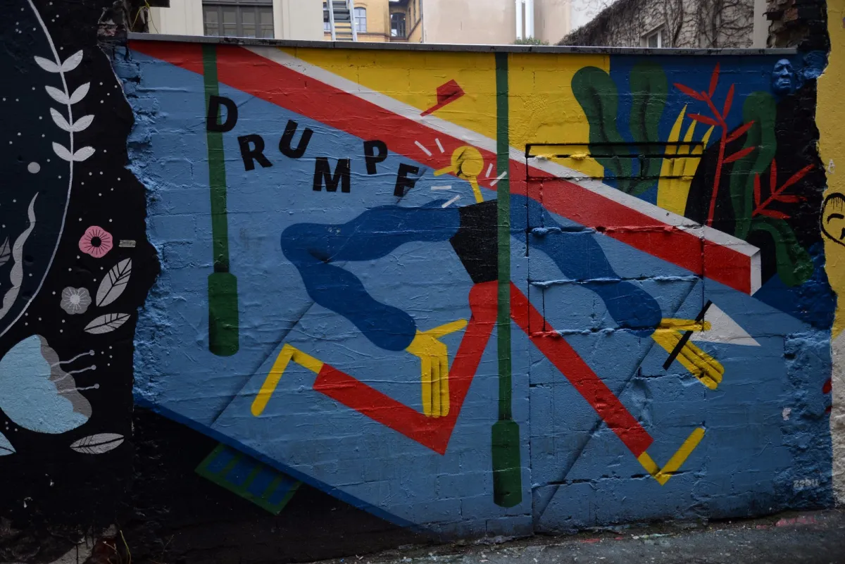 Bunte Wandmalerei mit abstrakten Formen und dem Wort 'DRUMPF'.