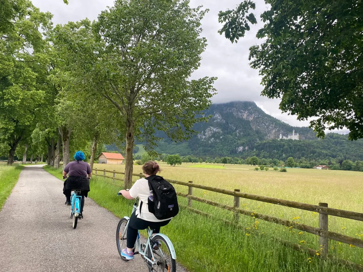 Zwei Personen fahren Fahrrad auf einem ländlichen Weg.