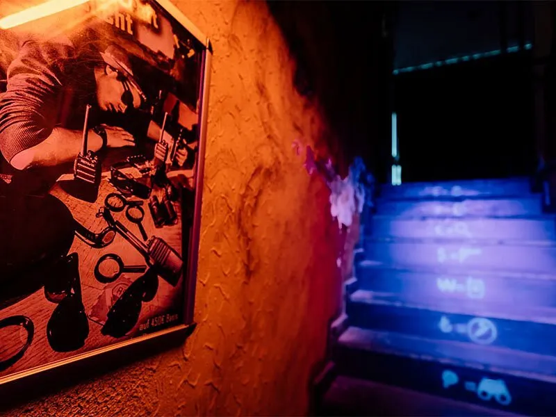 Poster an einer Wand neben einer Treppe mit blauer Beleuchtung.