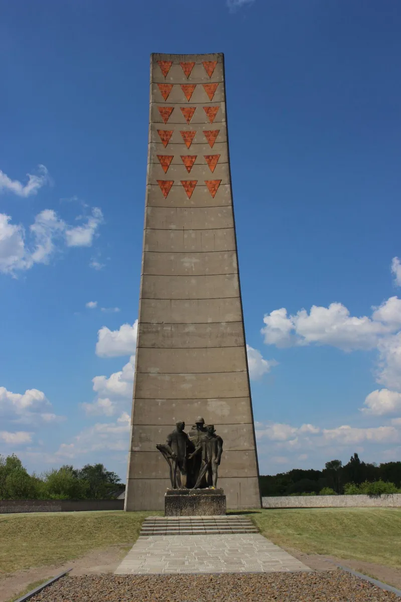 Denkmal mit Figuren und Turm im Hintergrund.