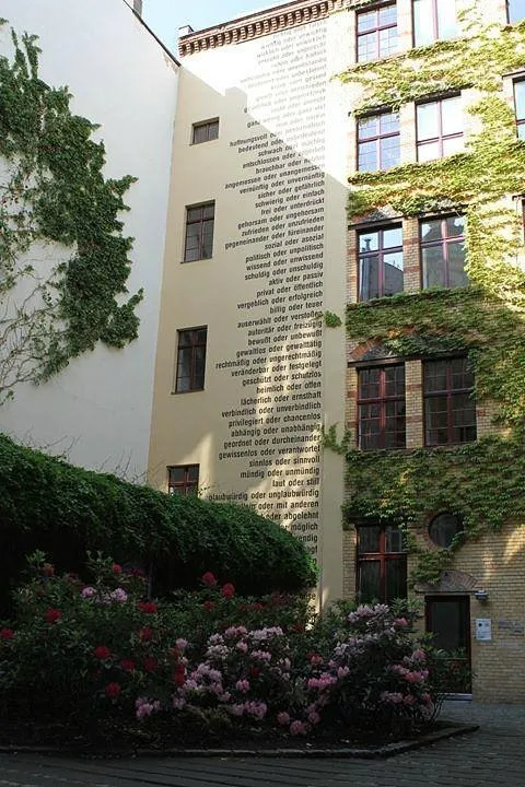 Innenhof mit bepflanzter Fassade und Wandtext.